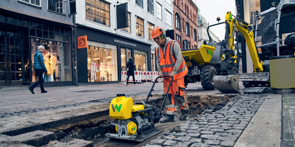un uomo al lavoro in un cantiere nel centro della città con una piastra vibrante leggera