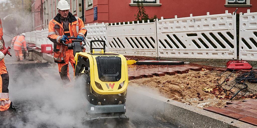 operaio edile al lavoro con una piastra vibrante in un cantiere nel centro città