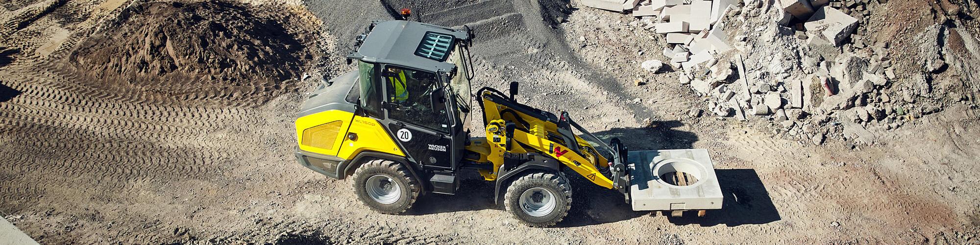 Pala gommata Wacker Neuson WL750p ad alte prestazioni mentre trasporta un elemento in calcestruzzo in un cantiere.